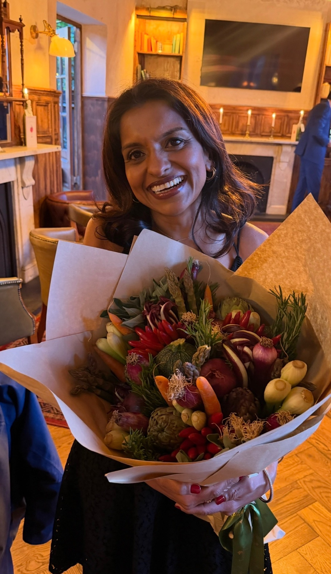 Sabina smiling with a bouquet of vegetables