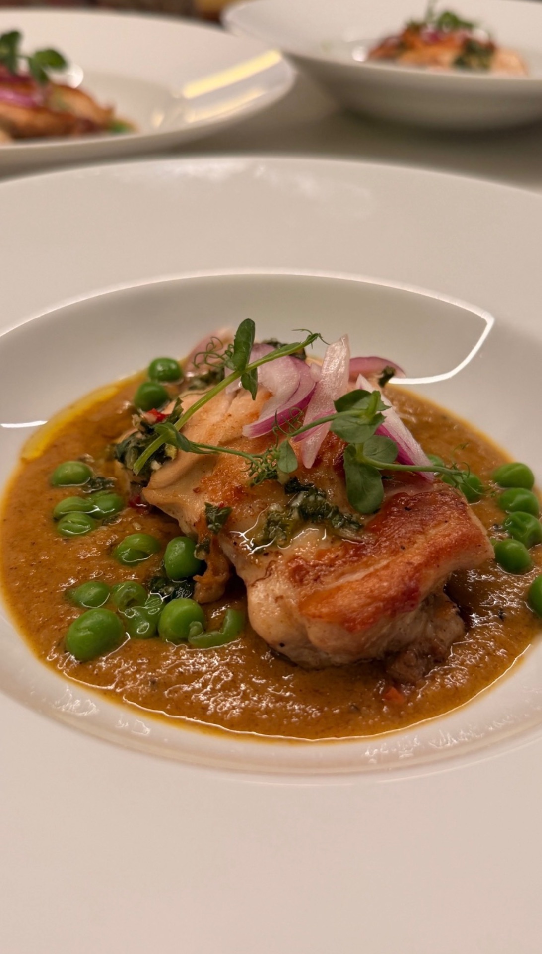 Plated prawn course with peas, pickled onion and herbs