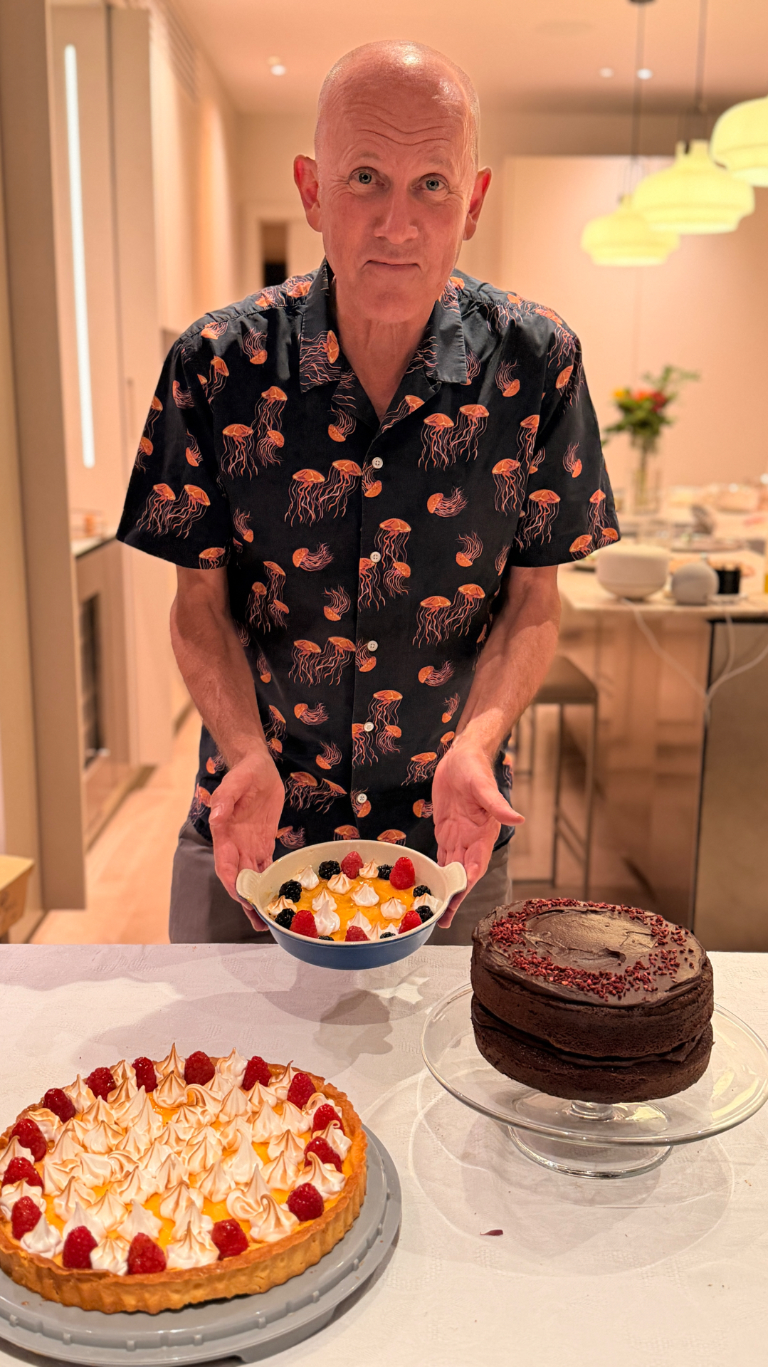Peter presenting desserts at a birthday, with a raspberry tart and chocolate cake