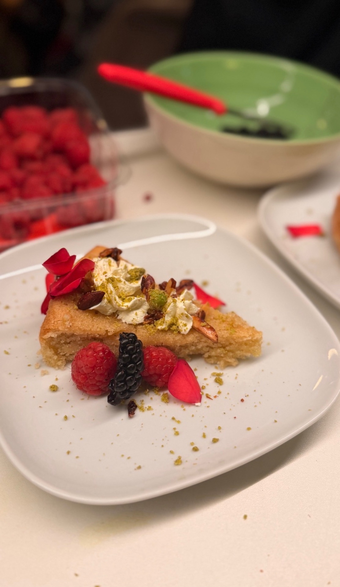 Dessert with cream, berries, pistachios and rose petals