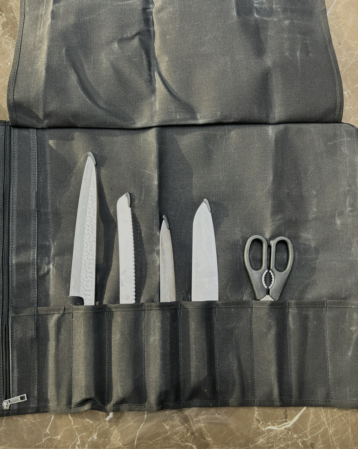Sabina's knives and kitchen scissors packed in an open knife roll