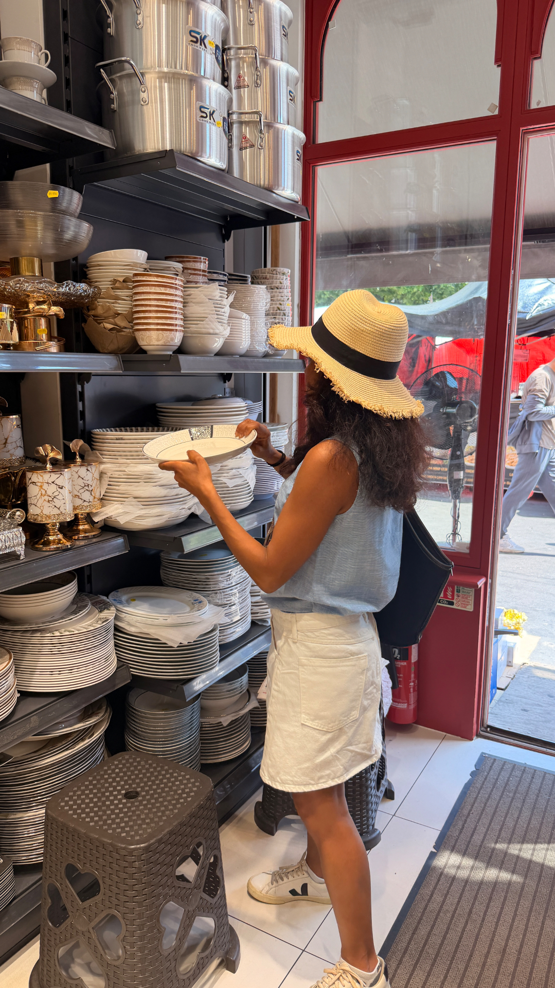 Sabina choosing plates at a market while planning an event