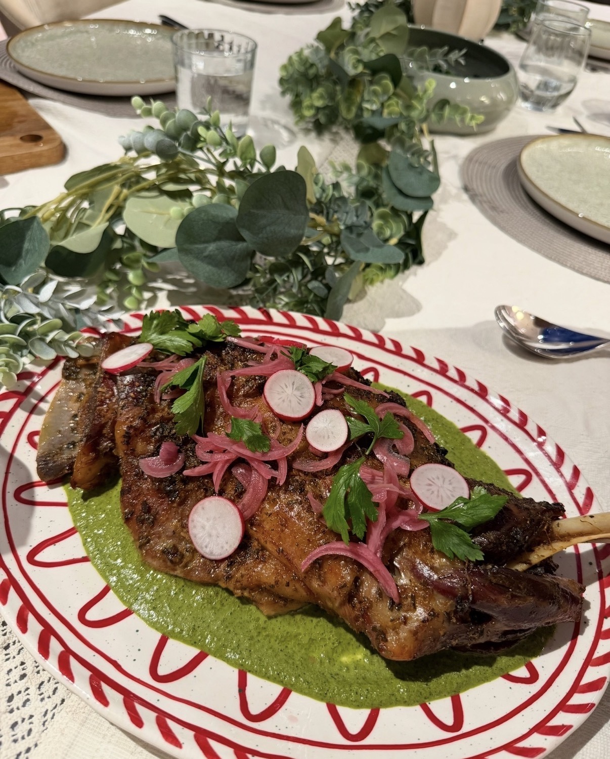 A roast platter with green sauce, pickled onion and radish at a private dinner