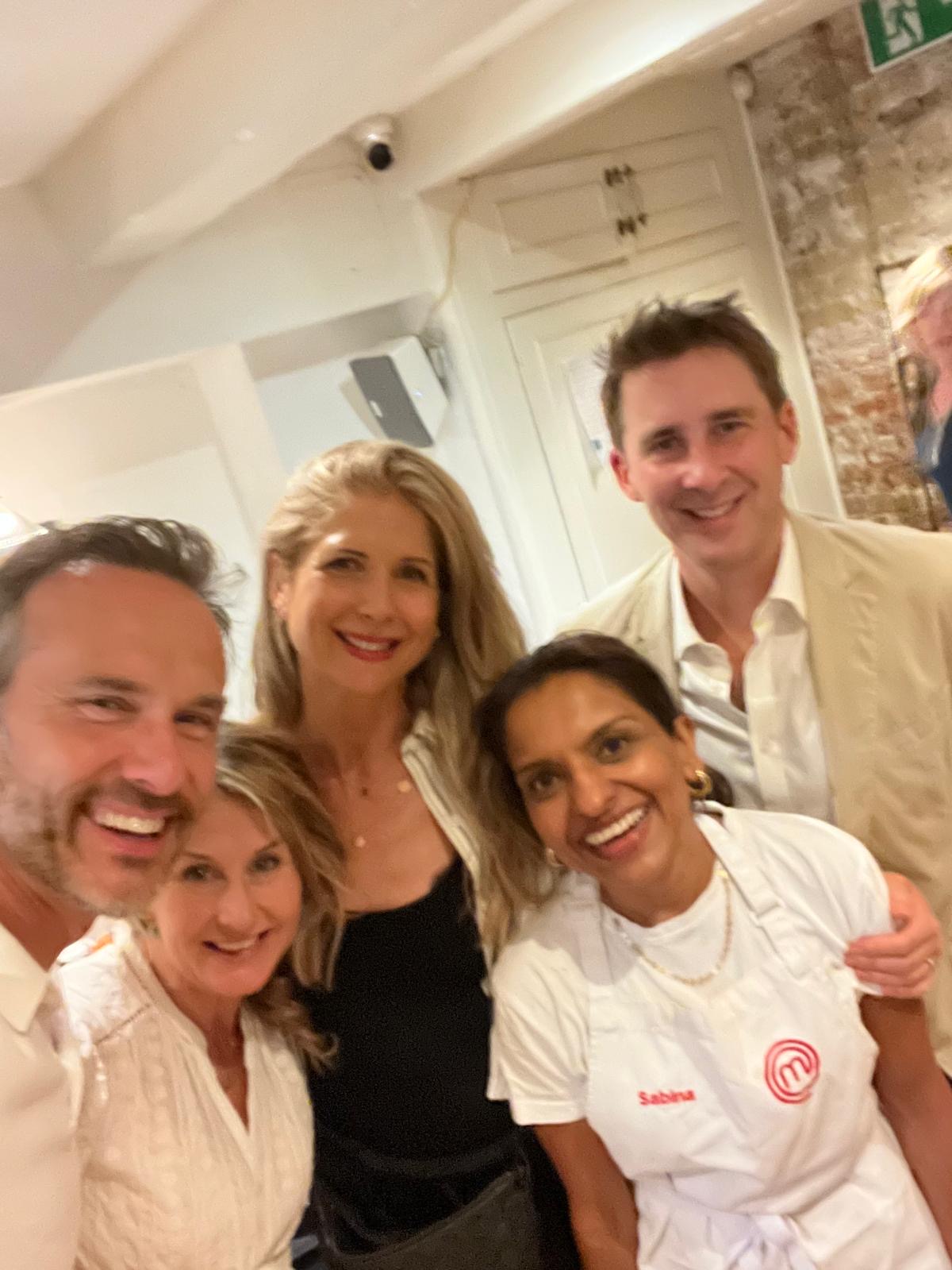 Sabina in her MasterChef apron smiling with supper-club guests