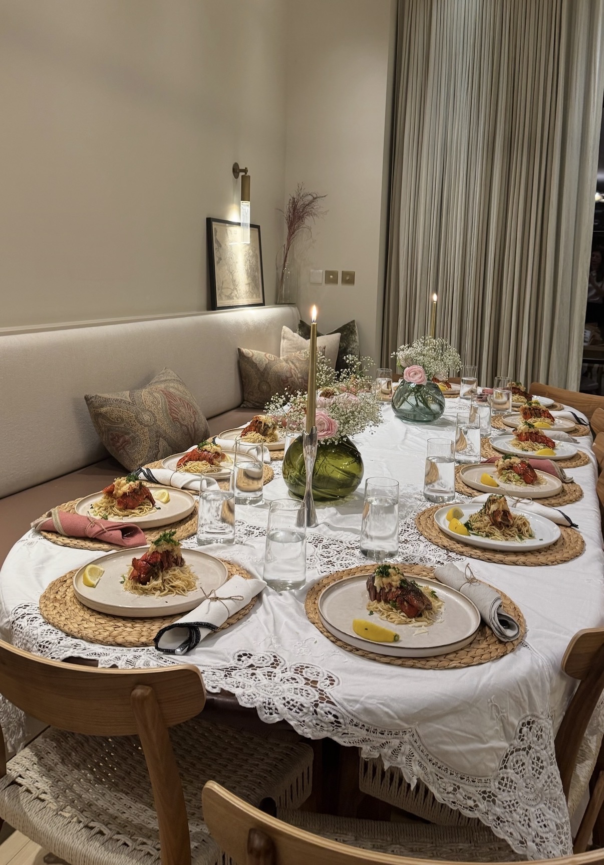 A candlelit private dinner table set with flowers and plated lobster pasta