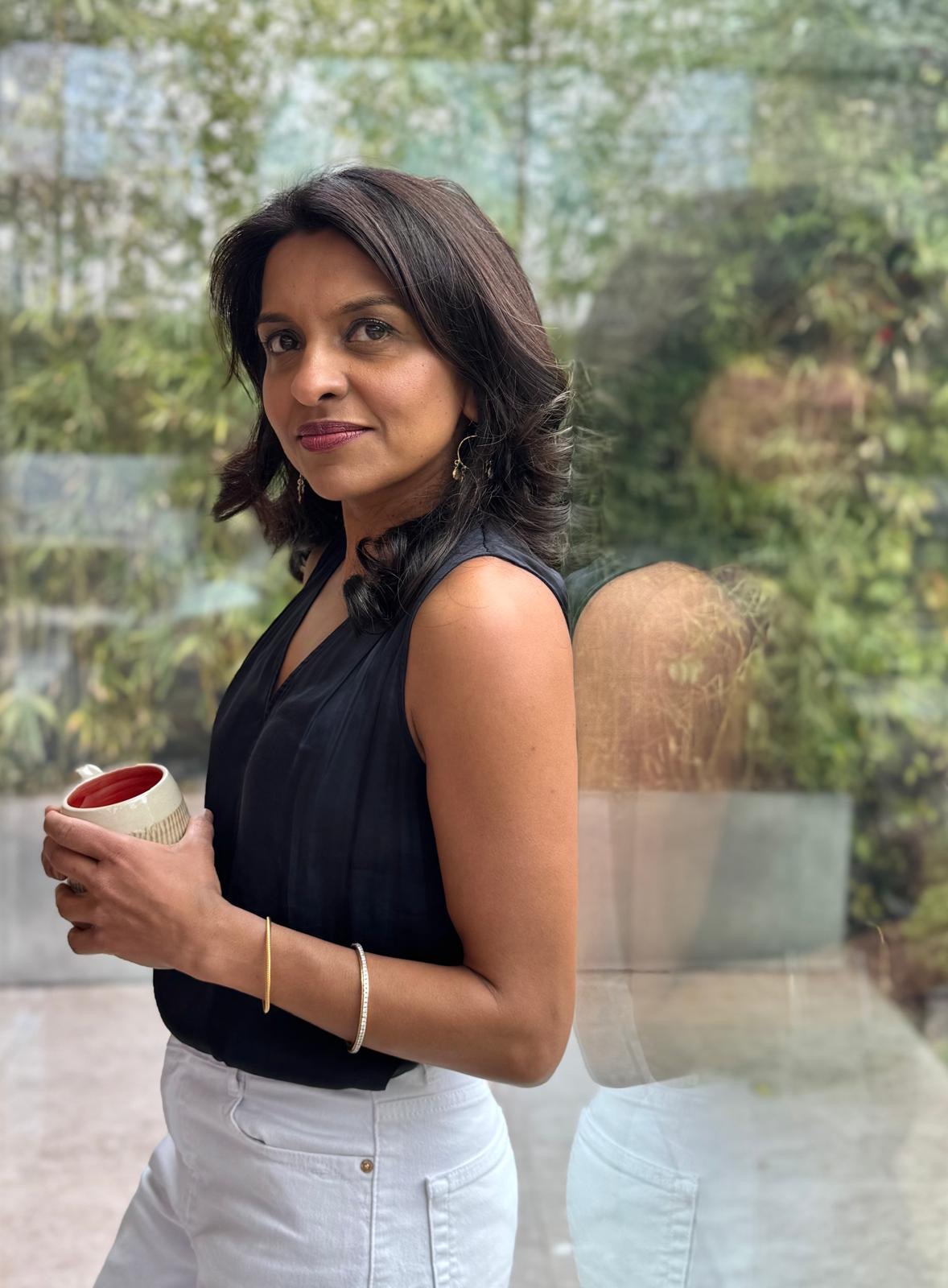 Sabina holding a mug beside a window