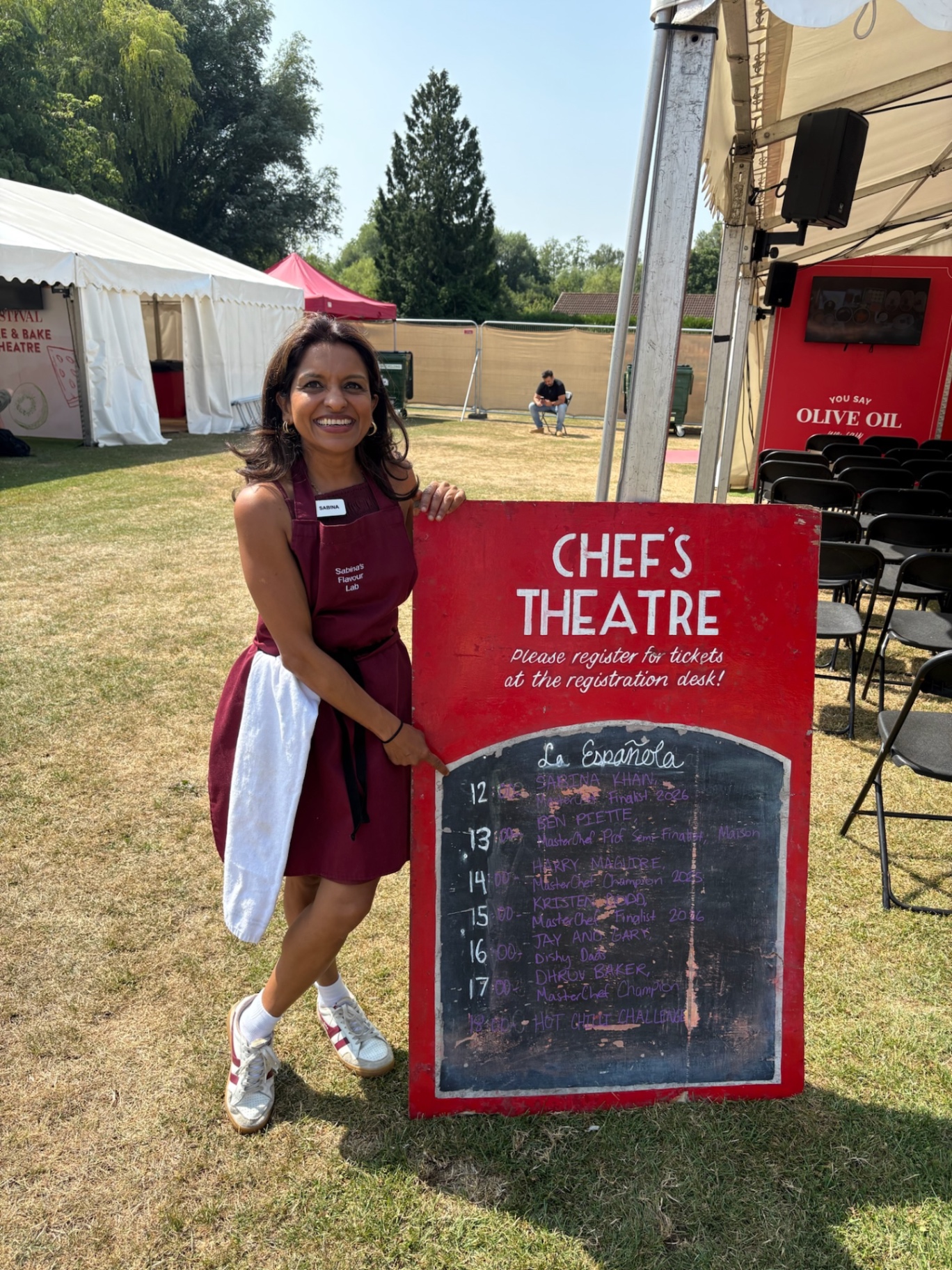 Sabina beside the Chef's Theatre lineup board at Foodies Festival, where she is billed as the first host of the day