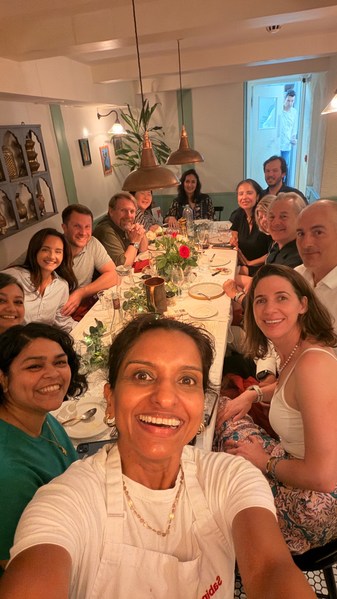 Sabina taking a group photograph with guests around the supper-club table